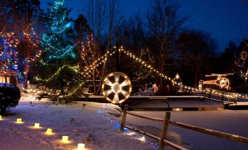 A winter scene with a decorated tree, glowing lights, and a snowy path lined with candles at dusk.