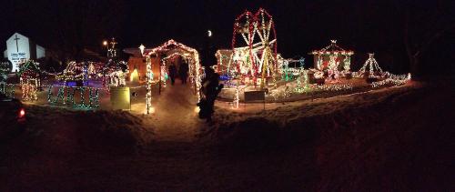 A festive display of colorful Christmas lights and decorations in a snowy outdoor setting at night.