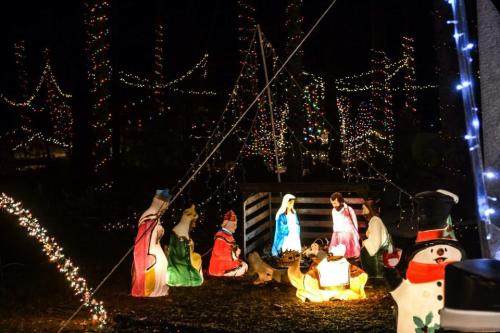 A festive outdoor scene featuring a illuminated nativity display surrounded by colorful holiday lights.