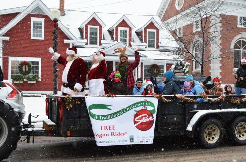 A festive parade float with Santa and children, surrounded by snow, promoting free wagon rides in Stowe.