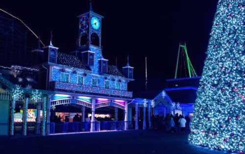 A festive scene at night featuring a brightly lit building and a large decorated Christmas tree.
