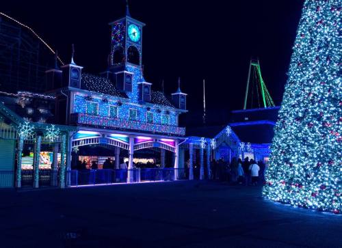 A festive scene at night featuring a brightly lit building and a large decorated Christmas tree.