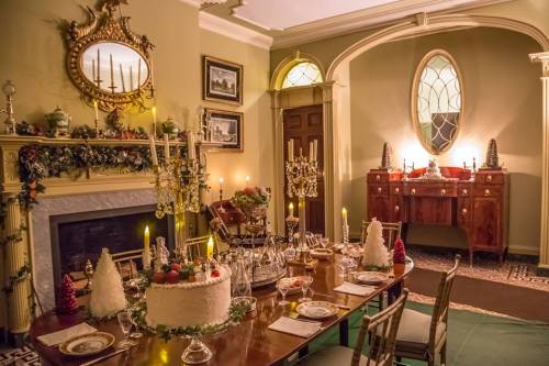 A beautifully decorated dining room with a festive table, candles, and a cake, set for a holiday celebration.