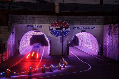 Two illuminated tunnel entrances with colorful lights, labeled "Infield Exit" and "Infield Entrance," at night.