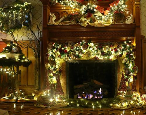 A beautifully decorated fireplace adorned with garlands, ornaments, and twinkling lights for the holiday season.