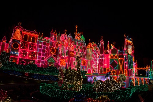 A brightly lit castle adorned with colorful lights, set against a dark night sky, creating a festive atmosphere.
