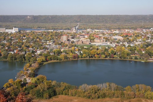 Aerial view of a town by a river, surrounded by colorful autumn trees and a calm lake.
