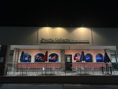 Exterior of Puerto Vallarta Mexican Restaurant at night, featuring illuminated windows and outdoor seating.