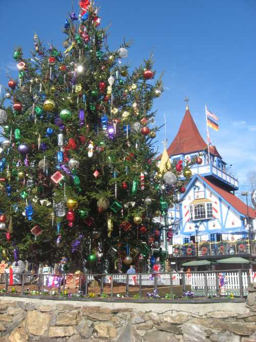 A decorated Christmas tree in front of a colorful, festive building under a clear blue sky.