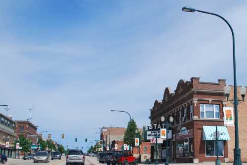 A street view of a small town with shops, traffic lights, and a clear blue sky.