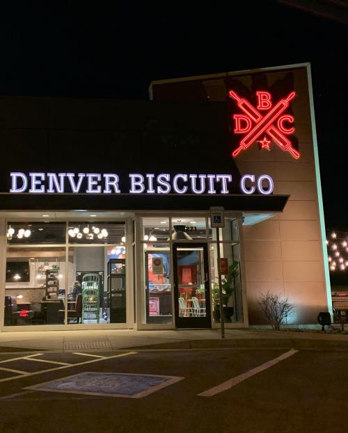 Exterior of Denver Biscuit Co. at night, featuring a lit sign and modern design.