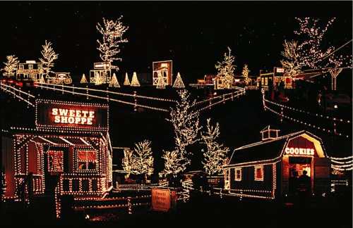 A festive display of illuminated buildings and trees, creating a cheerful holiday scene at night.