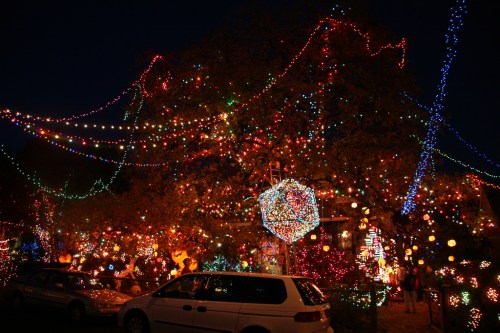 A vibrant display of colorful holiday lights adorning trees and buildings at night, creating a festive atmosphere.
