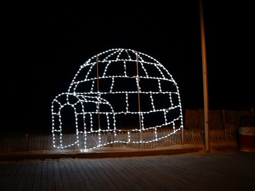 A glowing igloo made of white lights, set against a dark night sky.