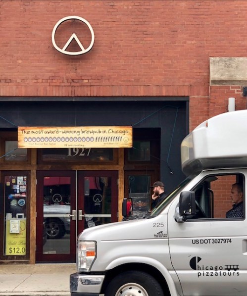 A brewery entrance in Chicago with a sign reading "The most award-winning brewpub in Chicago" and a delivery van nearby.
