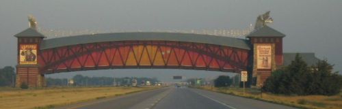 A colorful archway bridge spans a highway, featuring decorative elements and advertisements on its sides.