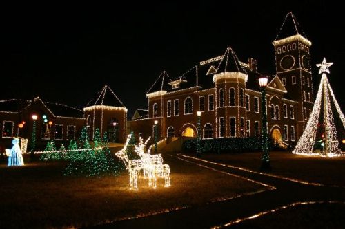 A beautifully lit building adorned with Christmas lights, featuring a decorated tree and glowing reindeer in the foreground.