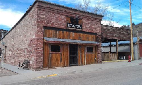 Historic stone building with wooden accents and a sign, located on a quiet street with benches and a fire hydrant nearby.