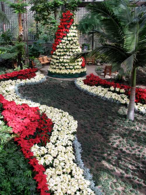 A beautifully arranged garden featuring a spiral path of red and white flowers, with a floral Christmas tree centerpiece.