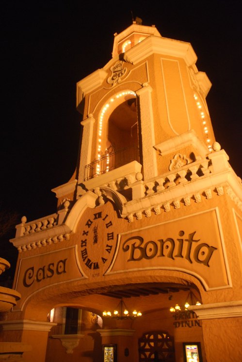 The brightly lit entrance of Casa Bonita, featuring a clock and decorative architecture, at night.