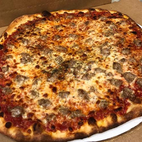 A close-up of a freshly baked pizza topped with cheese and meatballs, resting in a pizza box.