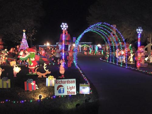 Colorful holiday light display featuring festive decorations, a Christmas tree, and an archway of lights at night.