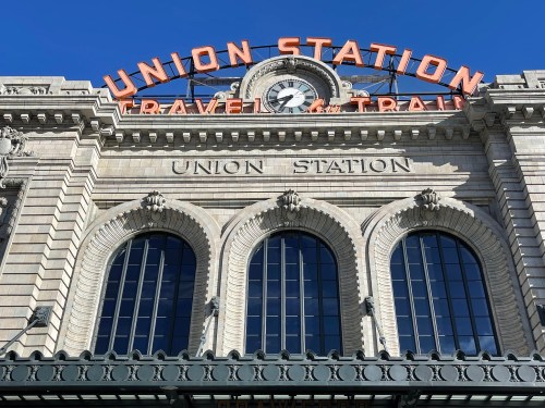 Historic Union Station building with a clock and bright orange signage against a clear blue sky.
