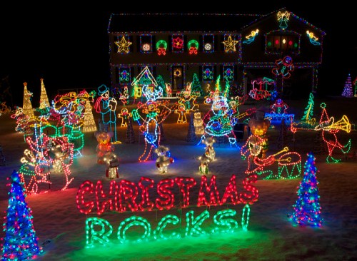 A festive display of colorful Christmas lights featuring animated figures, trees, and a sign that says "Christmas Rocks!"