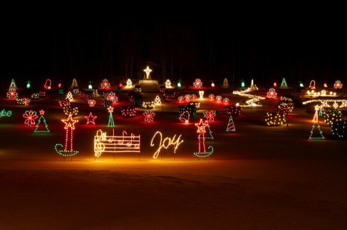 A festive display of colorful Christmas lights in various shapes, including trees, stars, and the word "Joy."
