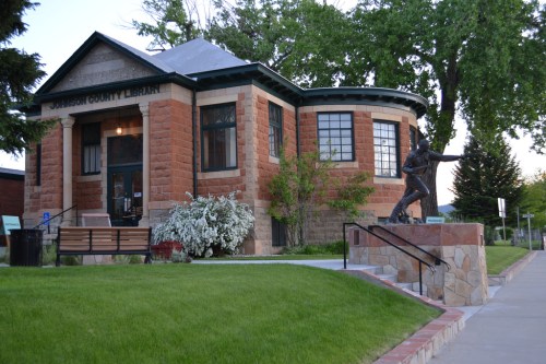 Historic building of the Jackson County Library, featuring a statue and lush green landscaping.