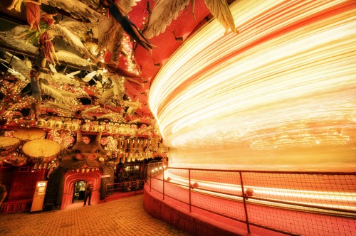 A vibrant amusement park scene with a spinning ride, illuminated by bright lights and surrounded by colorful decorations.