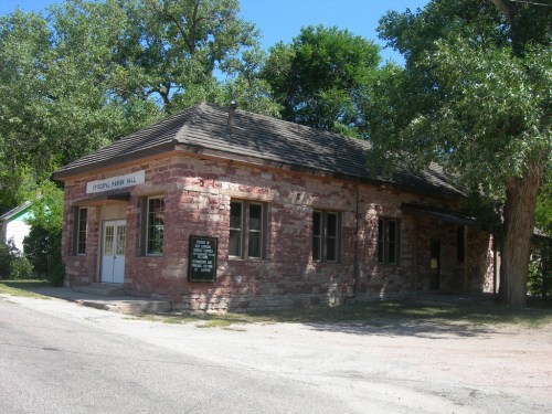 Historic stone building with a sloped roof, surrounded by trees, featuring a sign that reads "Cypress Mill Hall."