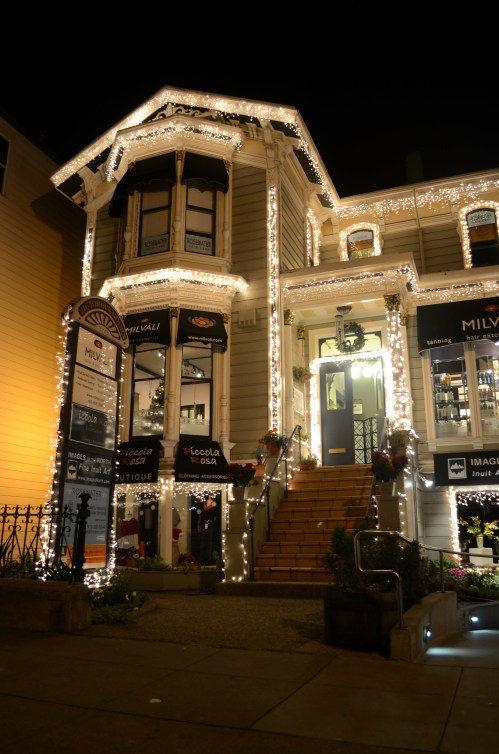 A beautifully lit building at night, adorned with festive lights and decorations, showcasing a welcoming entrance.