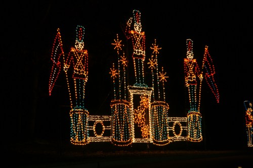 Colorful holiday lights display featuring toy soldiers and stars against a dark background.