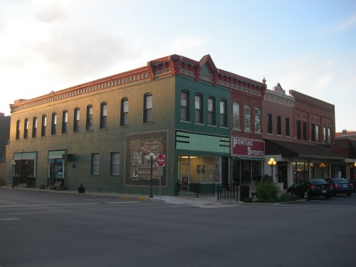 Historic buildings in a small town, featuring colorful facades and storefronts, with a clear sky in the background.