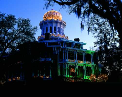 A grand, illuminated mansion with a golden dome, surrounded by trees and festive lights at dusk.