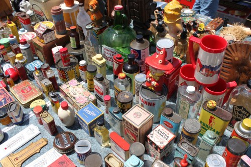 A colorful assortment of vintage bottles, cans, and collectibles displayed at a market.