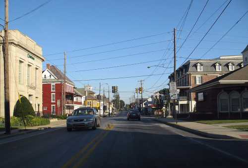 A street view showing buildings, traffic lights, and cars on a clear day in a small town.