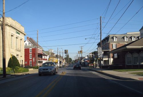 A street view showing buildings, traffic lights, and cars on a clear day in a small town.