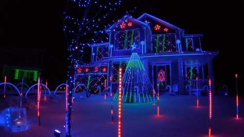 A brightly lit house decorated with colorful Christmas lights, featuring a glowing tree and festive displays in the yard.