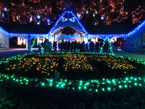 A festive scene with a crowd in front of a building adorned with colorful holiday lights and decorations.