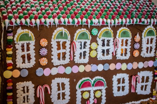 A colorful gingerbread house decorated with candy, icing, and gumdrops, featuring windows and a festive roof.