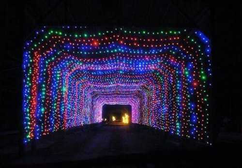 A colorful tunnel of lights in red, green, and blue, creating a festive atmosphere in a dark setting.