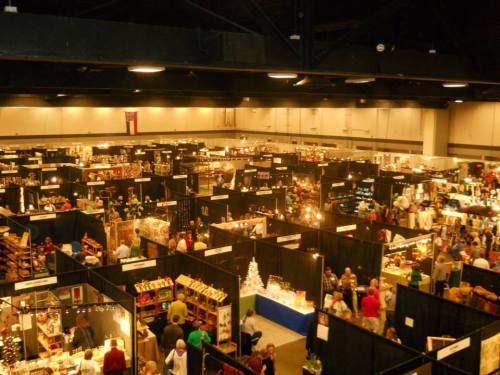 Aerial view of a bustling indoor market with numerous booths and visitors exploring various crafts and goods.