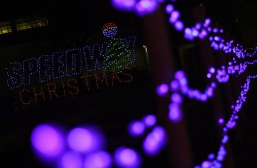 Colorful Christmas lights illuminate a festive display reading "Speedway Christmas" in a nighttime setting.