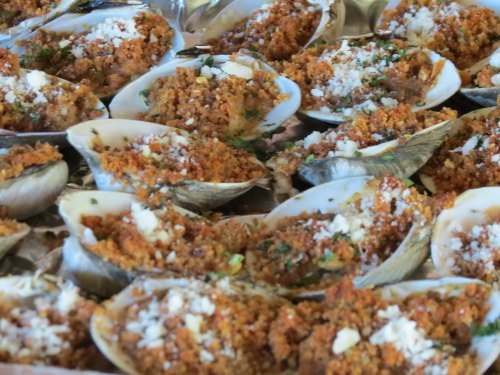 A close-up of baked stuffed clams topped with breadcrumbs and herbs, arranged neatly on a platter.