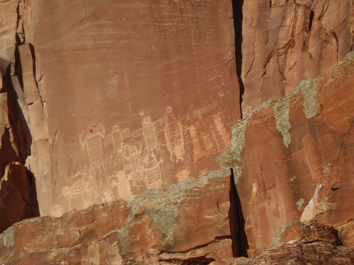 Petroglyphs carved into a rocky surface, depicting figures and symbols in earthy tones.