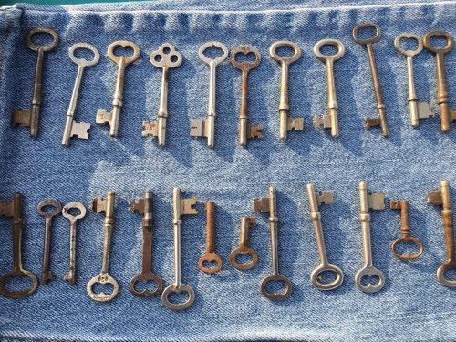 A collection of vintage keys arranged in rows on a denim background.
