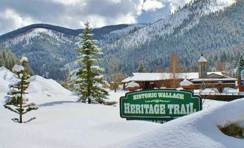 Snow-covered landscape with mountains in the background and a sign for the Historic Wallace Heritage Trail.