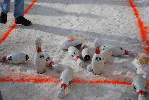 Bowling pins scattered on snow, with orange lines marking the playing area.